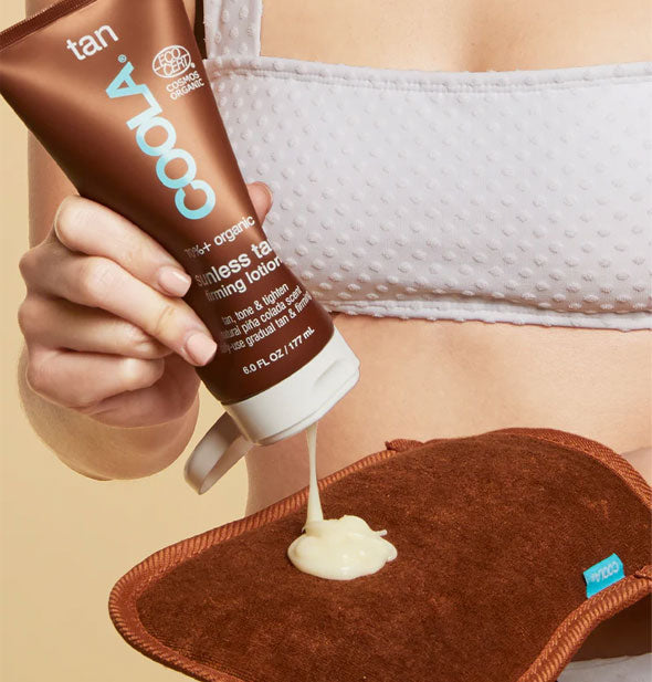 Model dispenses Coola Sunless Tan Firming Lotion onto a brown applicator mitt