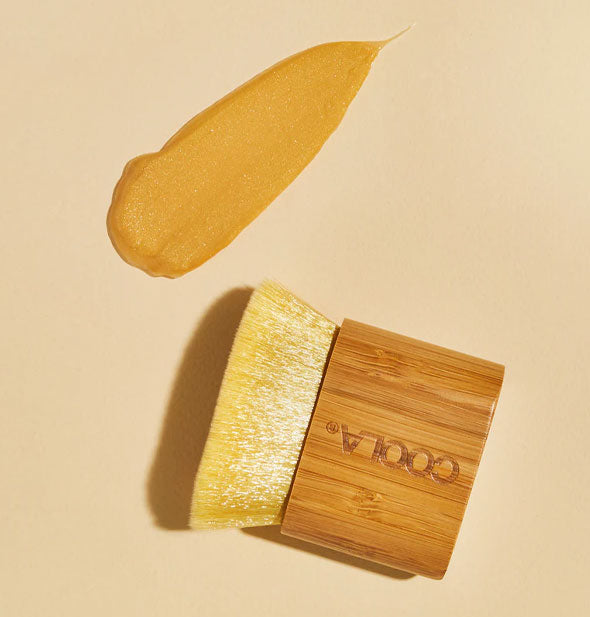 Wood-handled Coola Kabuki Brush next to an application of sunless tanner