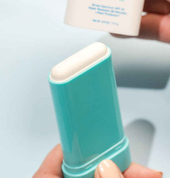 Model holds an opened tube of Coola Mineral Sunscreen Stick