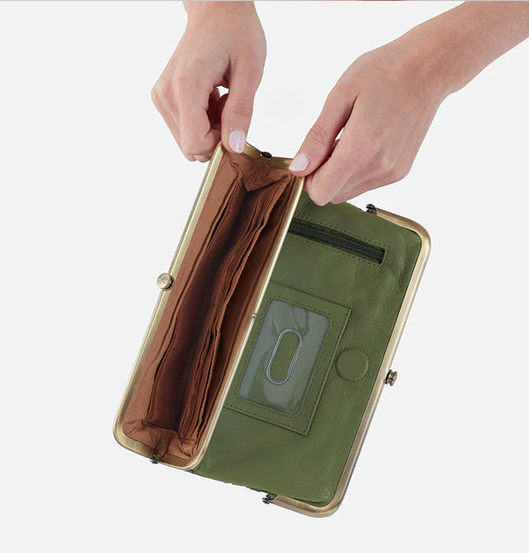 Model's hands hold open a section of green leather wallet with antiqued brass frame hardware and a brown interior