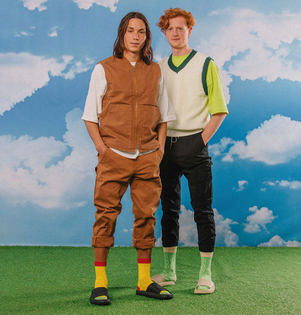 Models each wear a pair of Tasty Nachos crew socks with slide sandals against an astroturf and blue sky with white clouds backdrop