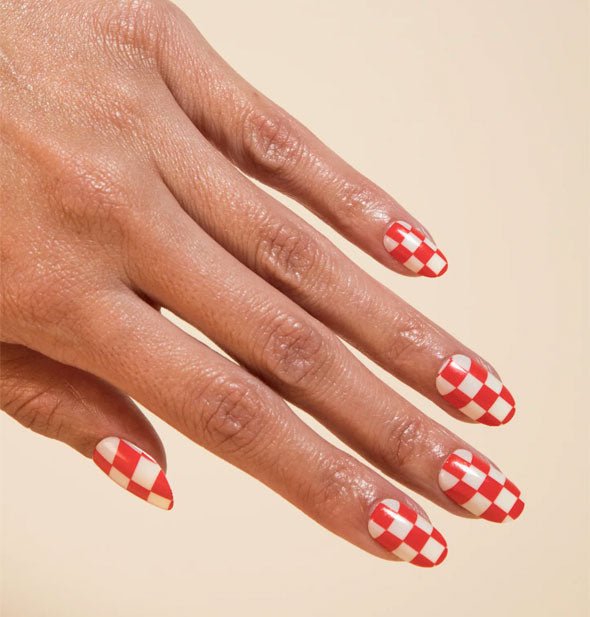 Model's hand wears a set of red and white checker print press-on nails