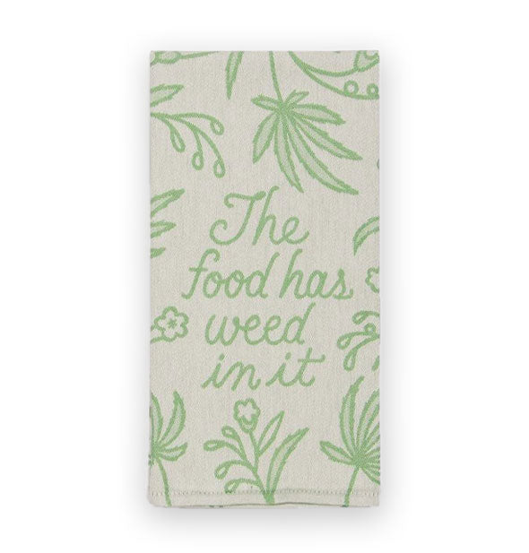 Beige dish towel with green botanical designs says, "The food has weed in it" in green script in the center