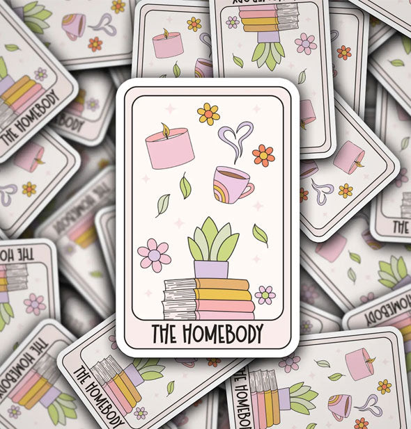 Rectangular stickers featuring illustration of books, plants, coffee mug with heart-shaped steam rising from it, and a candle say, "The Homebody"