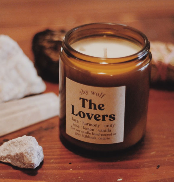 The Lovers amber glass jar candle on wooden surface with stones and other items