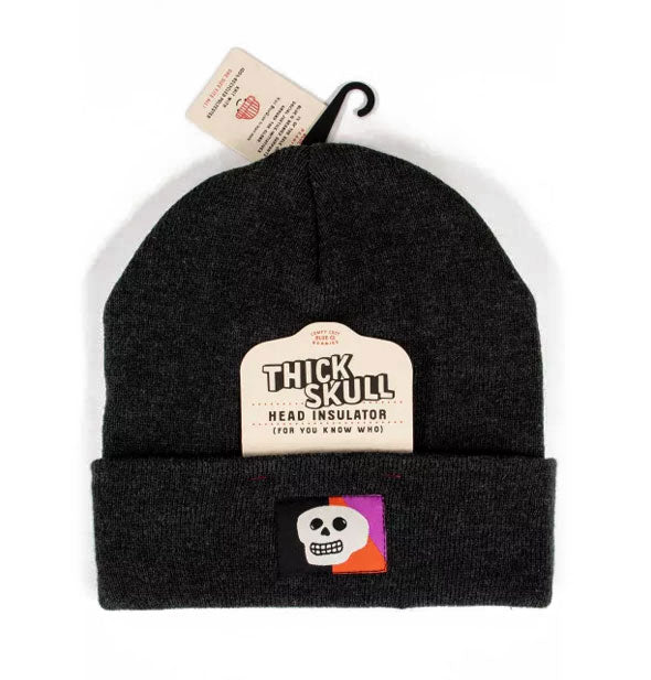Black knit beanie with colorful skull embroidery says, "Thick skull head insulator (for you know who)" on the attached tag