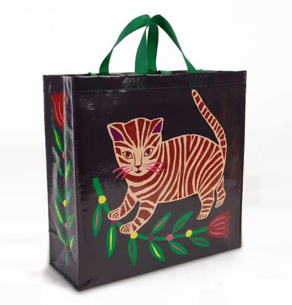 Black rectangular tote bag with green handles features illustration of a striped kitten and colorful flower