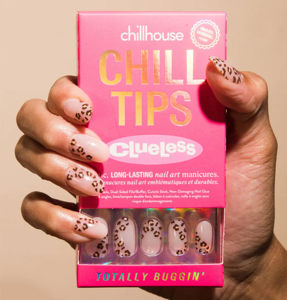 Model's hand wears a set of partial leopard print Chillhouse Chill Tips Clueless edition press-on nails and holds a pink box of the same design, called Totally Buggin'