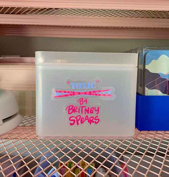 "Toxic" by Britney Spears sticker on a clear bin on wire shelf