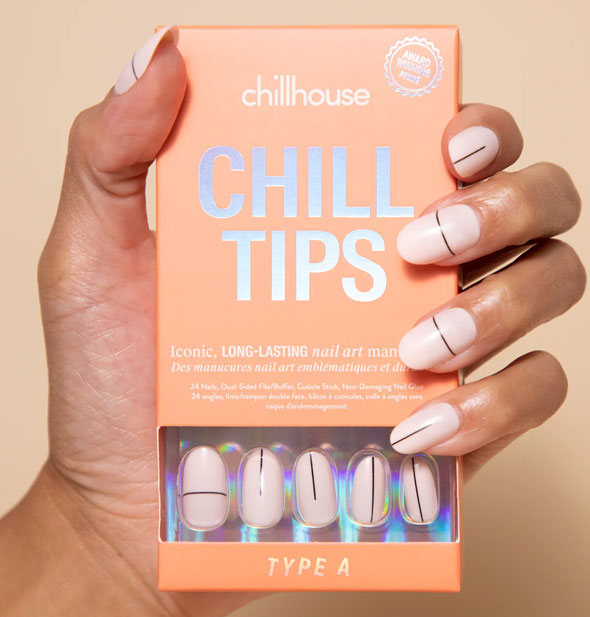 Model's hand wearing Type A Chillhouse Chill Tips press-on nails holds a box of the same style: whitish pink base with thin black lines