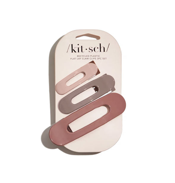 Three slotted hair clips in warm, earthy tones in glossy finishes are secured to a light pink Kitsch product card