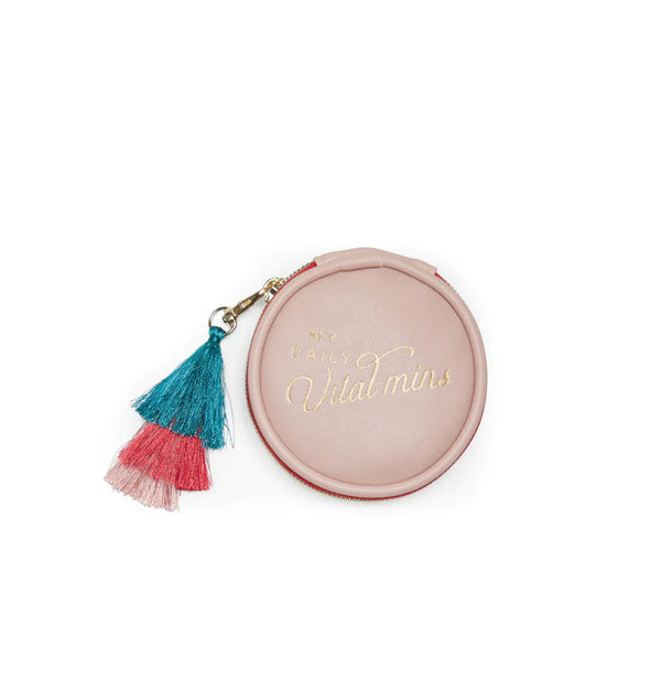 Round blush pink vegan leather pill case with tri-color tassel pull attached to a gold zipper says, "Daily Vital-mins" in metallic gold script
