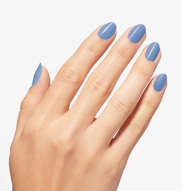 Model's hand wears a denim-like shade of blue nail polish