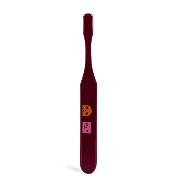 Back side of brown toothbrush with orange and pink smiling face graphics