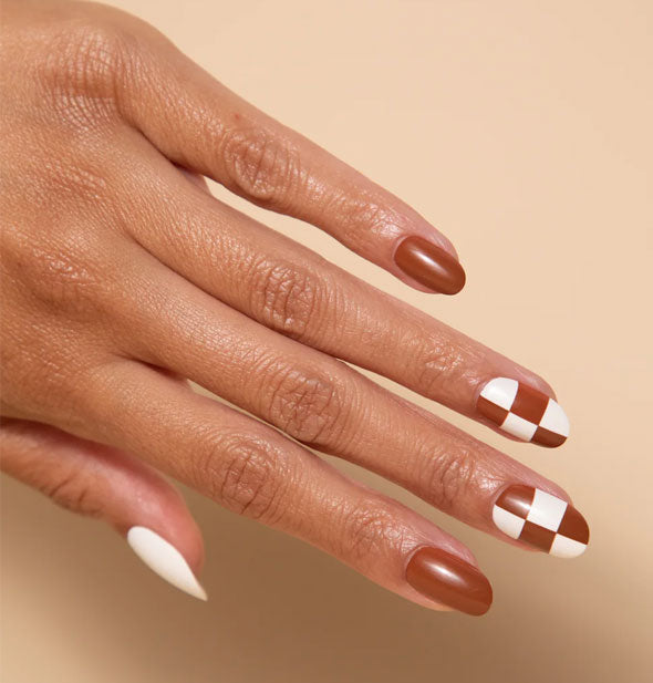 Model wears alternating brown, white, and brown and white checker print press-on nails