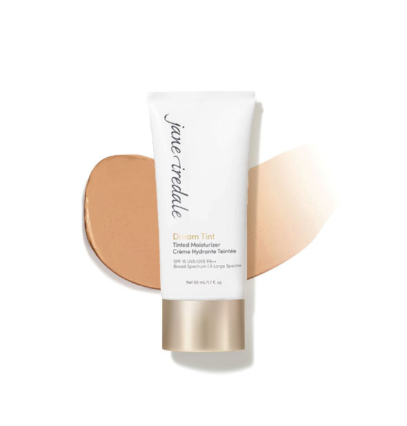 White and gold tube of Jane Iredale Dream Tint Tinted Moisturizer with enlarged smeared product application behind in shade Warm Bronze