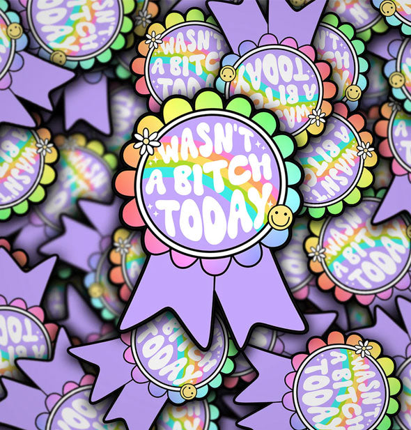 Pile of purple stickers illustrated to resemble prize ribbons with rainbow fringe say, "Wan't a Bitch Today" in white bubble lettering flanked by a smiley face and small white flower