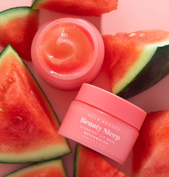 One closed and one opened pot of Watermelon NCLA Beauty brand Beauty Sleep Overnight Lip Mask staged with cut pieces of watermelon
