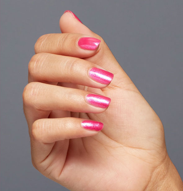 Model's hand wears a shimmery medium shade of pink nail polish