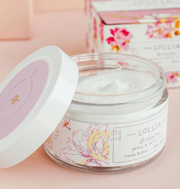 Opened jar of Lollia Breathe Body Butter reveals creamy white product inside; lid is set to the side and box is in the background