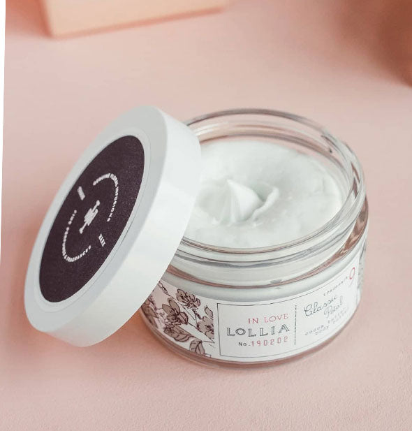 Opened jar of Lollia In Love Body Butter with lid set to the side reveals creamy white product inside