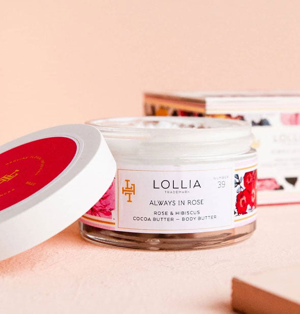 Opened jar of Lollia Always In Rose Body Butter with lid set to the side and box in the background