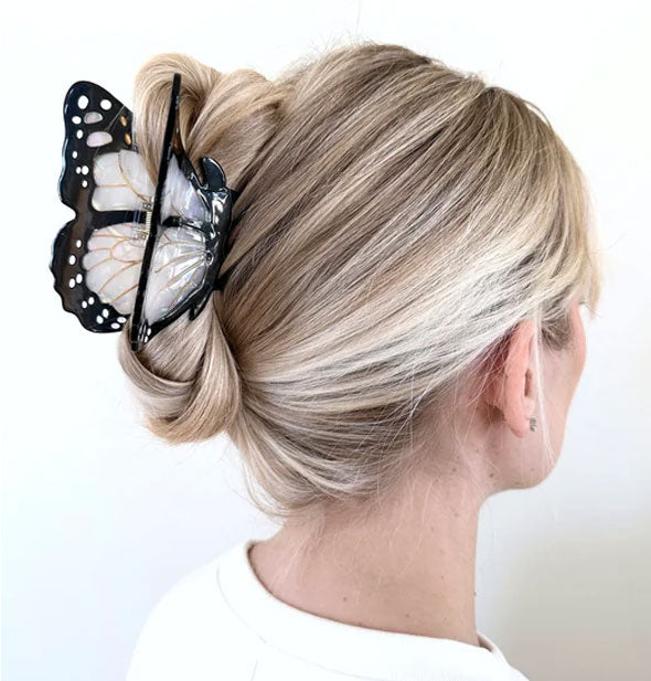 Model wears a white monarch butterfly claw clip in a twist updo