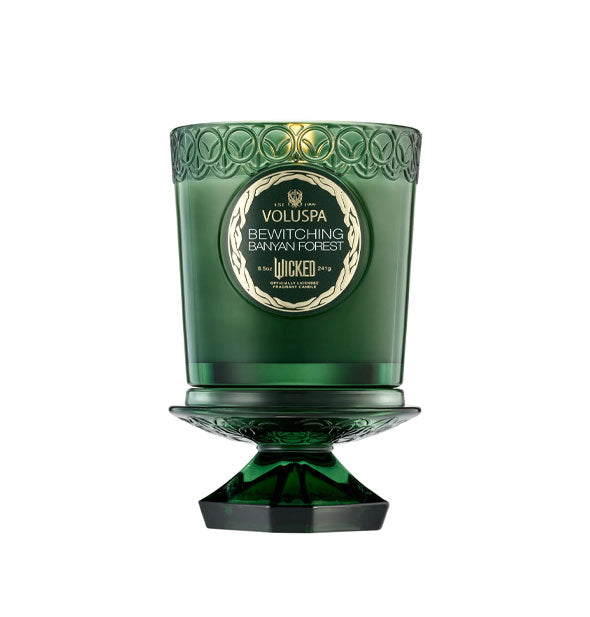 Lit Voluspa Bewitching Banyan Forest Wicked candle in embossed green glass jar with knobbed lid removed and used as a pedestal