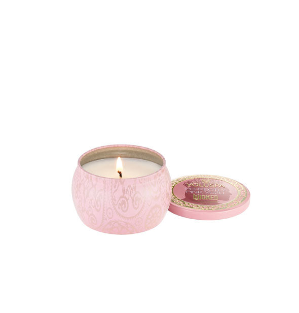 Lit Wicked-themed Voluspa Perfectly Pink Yuzu candle in a pink patterned tin with matching gold-framed lid removed and set to the side