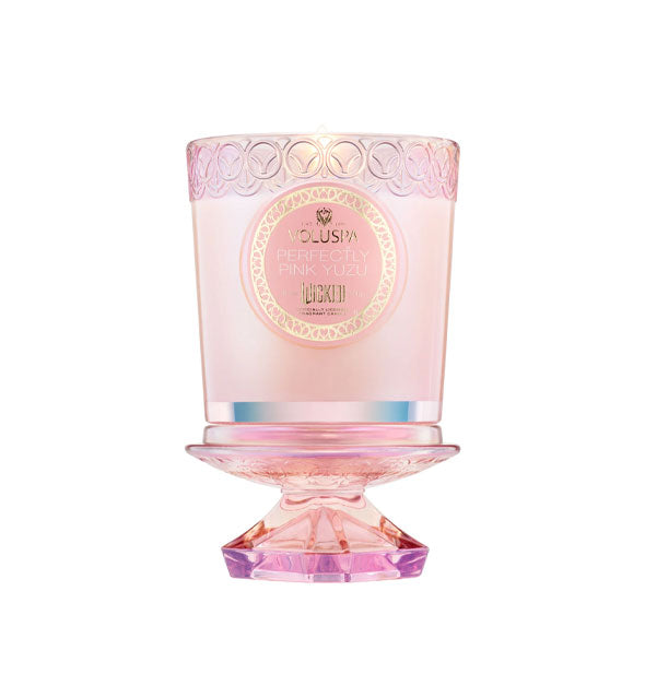 Lit Voluspa Perfectly Pink Yuzu Wicked candle in embossed pink glass jar with knobbed lid removed and used as a pedestal