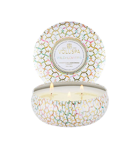 Round white Voluspa WIldflowers candle tin with lid removed and set upright behind the tin features multicolored pastel and gold lattice print