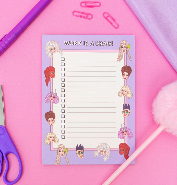 Work Is a Drag! drag queen notepad on a pink surface with other stationery supplies