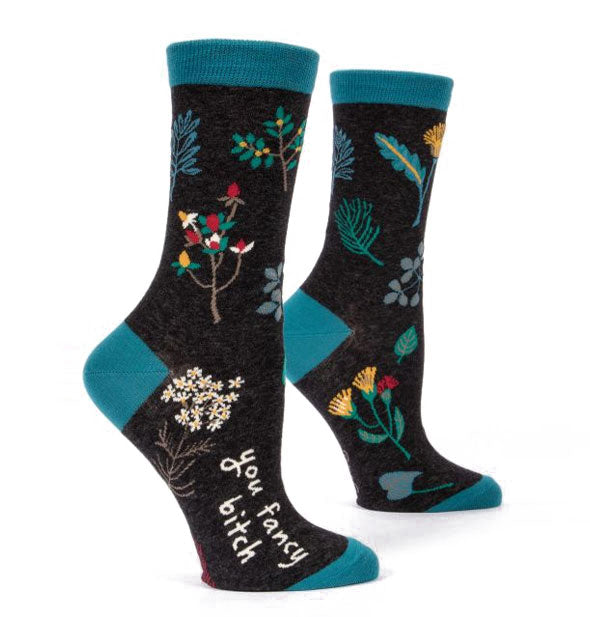 Crew socks with teal accents and floral illustrations say, "You fancy bitch" along the outer part of the foot near the toe