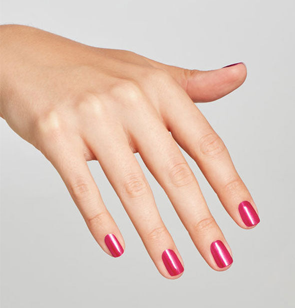 Model's hand wears a shimmery shade of fuchsia nail polish