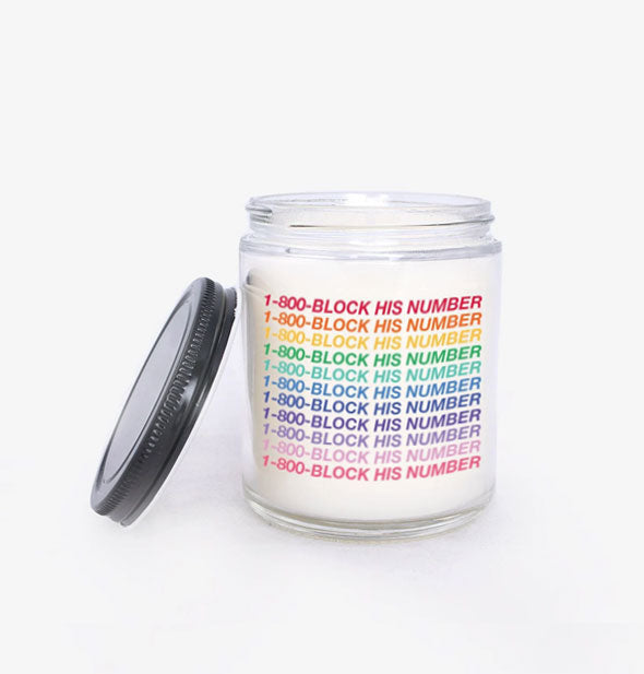 Glass jar candle is printed with, "1-800-Block His Number" in alternating rainbow colors and a black screw-top lid is set to the side