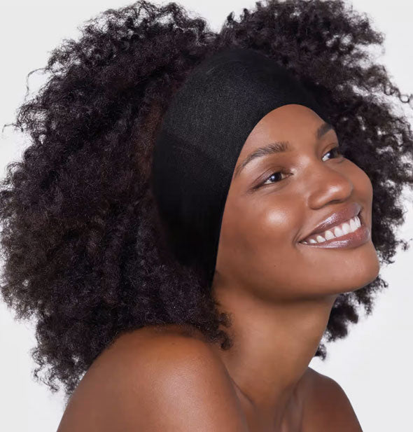 Smiling model wears a wide black fabric headband at the front of hair