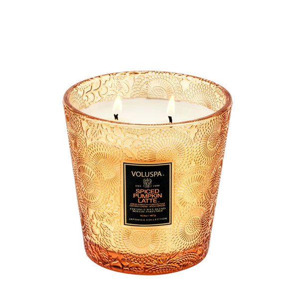 2-wick candle burning in a slightly tapered embossed orange glass container with black label.