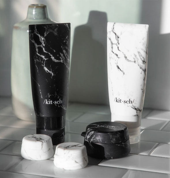 Set of marble-effect travel jars and bottles on white tile countertop
