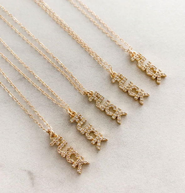 Five gold necklaces with rhinestone-encrusted "FUCK" pendants