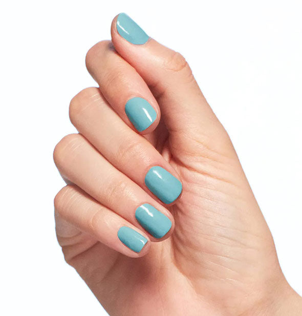 Model's hand wears a muted shade of turquoise nail polish