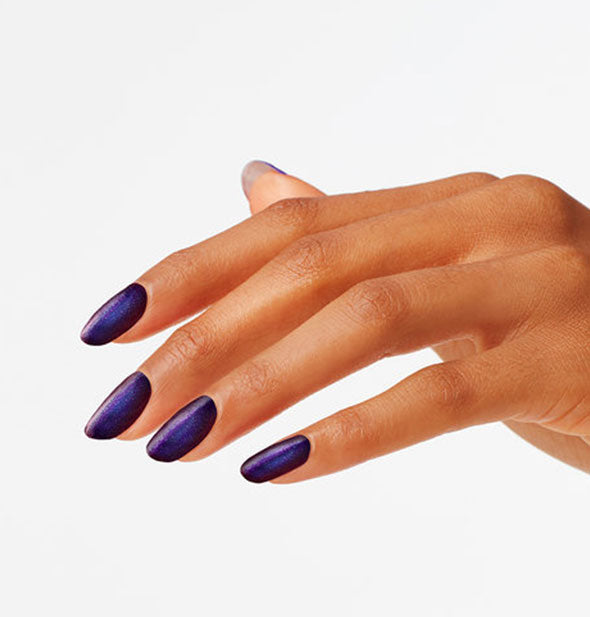 Model's hand wearing a dark blue shimmery shade of nail polish