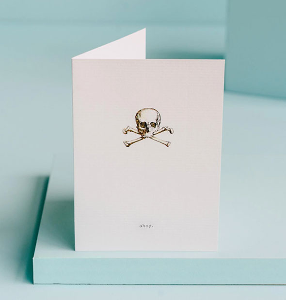 White greeting card with skull and crossbones illustration says "ahoy" at the bottom