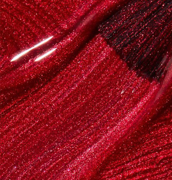 Shimmery red nail polish with brush tip drawn through it
