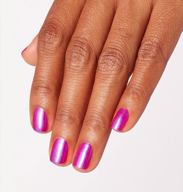 Model's hand wears an iridescent shade of pink-purple nail polish
