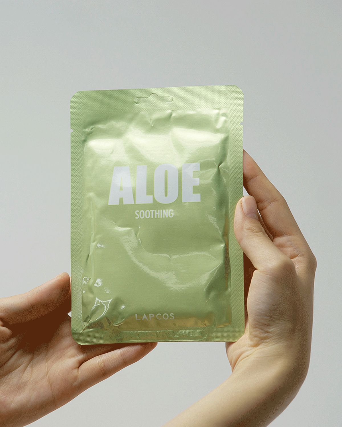Model opens an Aloe Soothing mask packet, removes the mask, and unfolds it