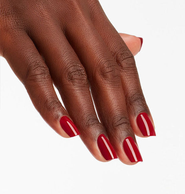 Model's hand wears a dark, rich shade of red nail polish