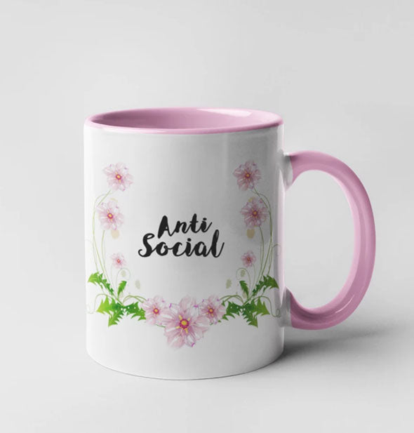 Coffee mug with pink interior, pink handle, floral accents, and black "Anti Social" lettering