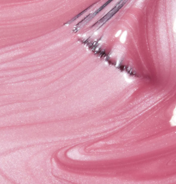 Closeup of pearlescent pink nail polish with brush tip drawn through it
