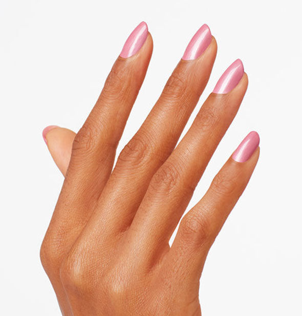 Model's hand wears a pearlescent pink shade of nail polish