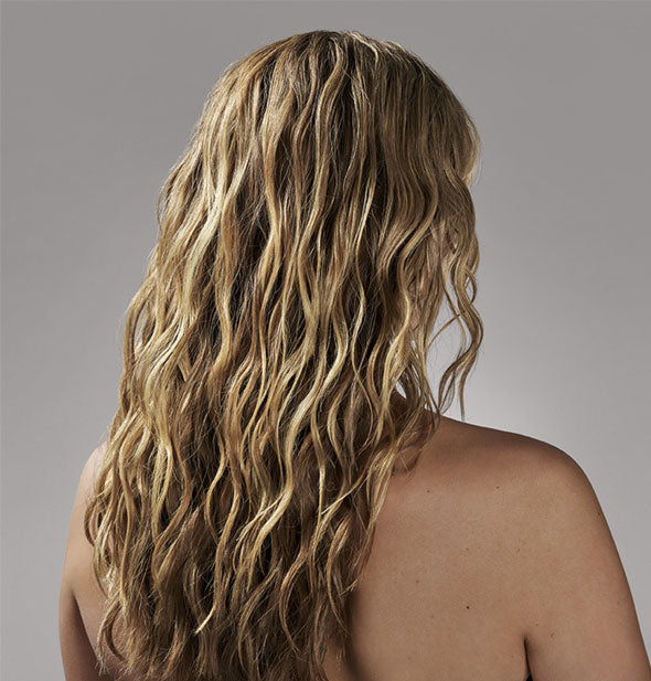 Model's hair shown from behind demonstrates results of using Oribe Après Beach Wave & Shine Spray